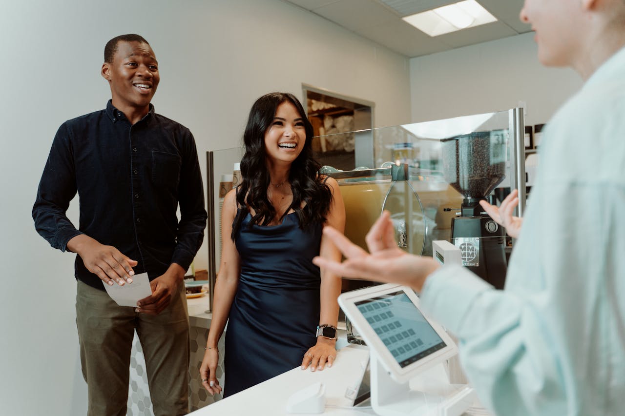 Smiling group at a coffee shop counter, engaging with a cashier, creating a warm atmosphere.
