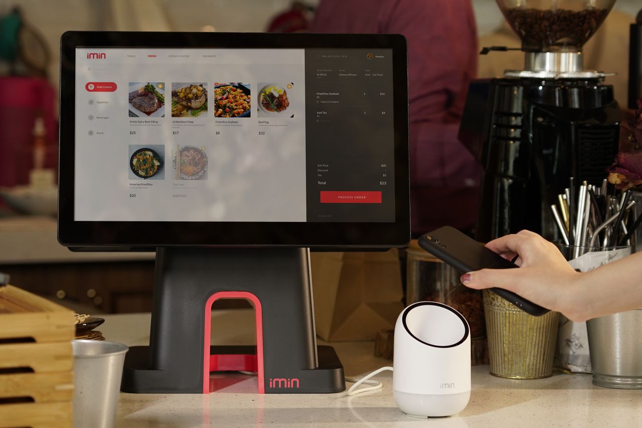 services-01 A modern point of sale system with contactless payment capability in a cafe setting.