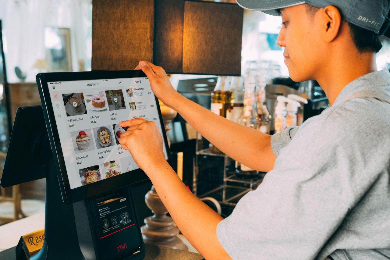 services-02 A cafe worker navigating a modern touchscreen system to manage orders efficiently.