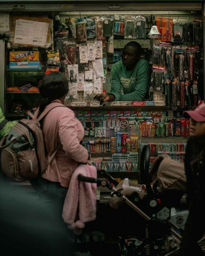 gallery-2 People interacting at a bustling street vendor kiosk filled with various merchandise.