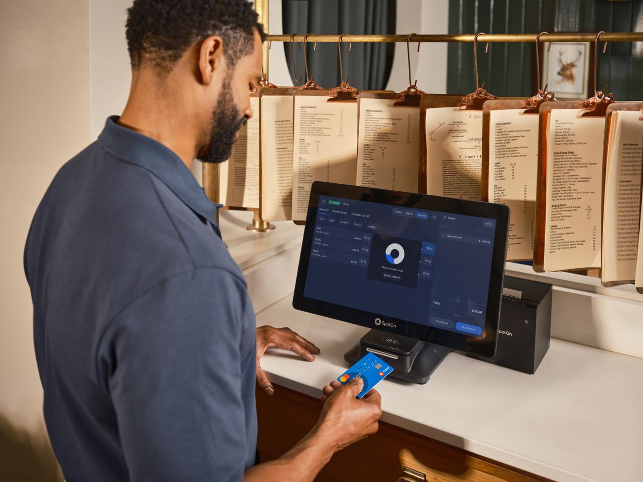 gallery-5 A restaurant staff member uses a POS system to process a credit card payment at the counter.