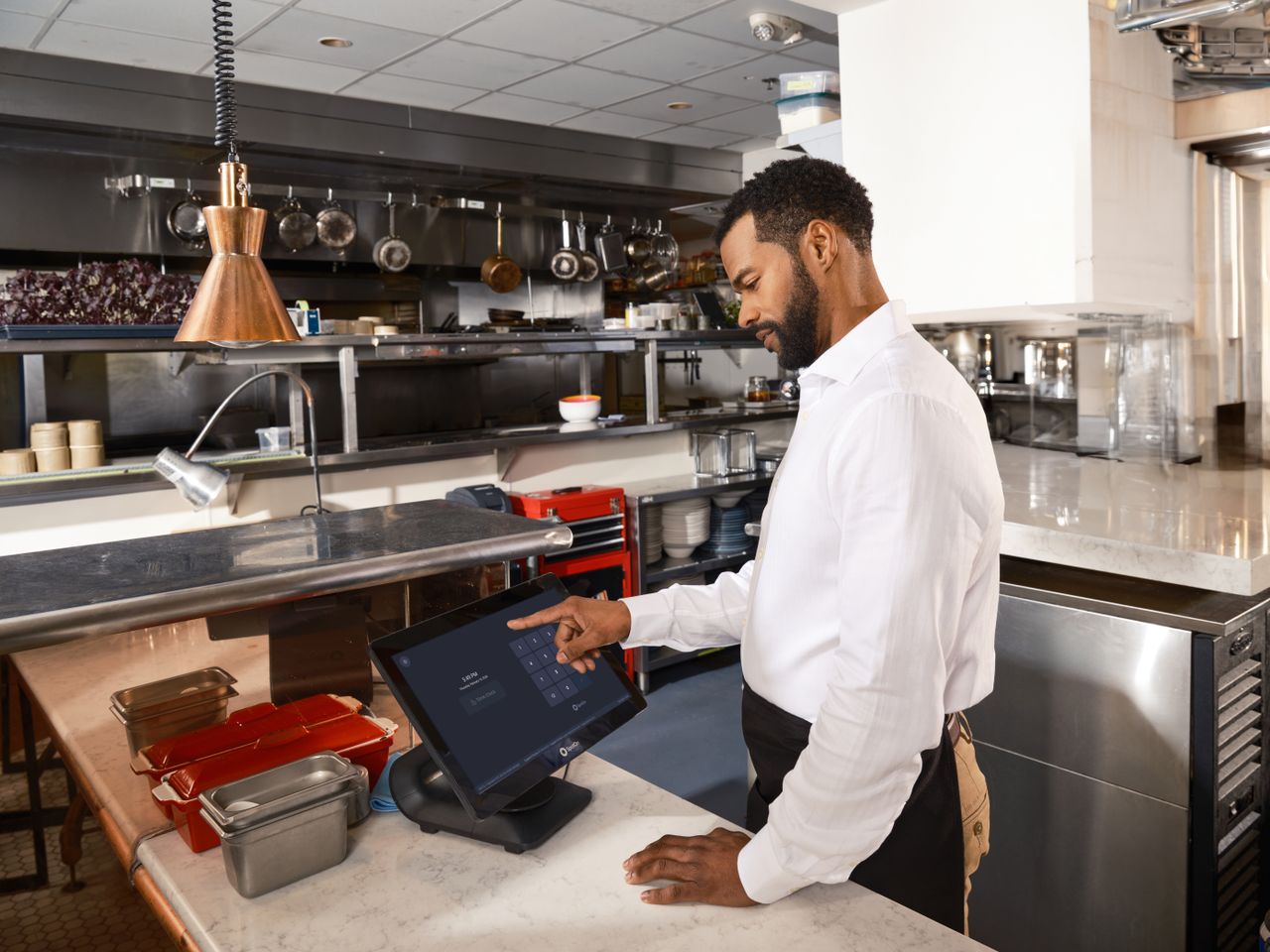 gallery-3 A restaurant worker operates a point of sale system in a commercial kitchen setting.